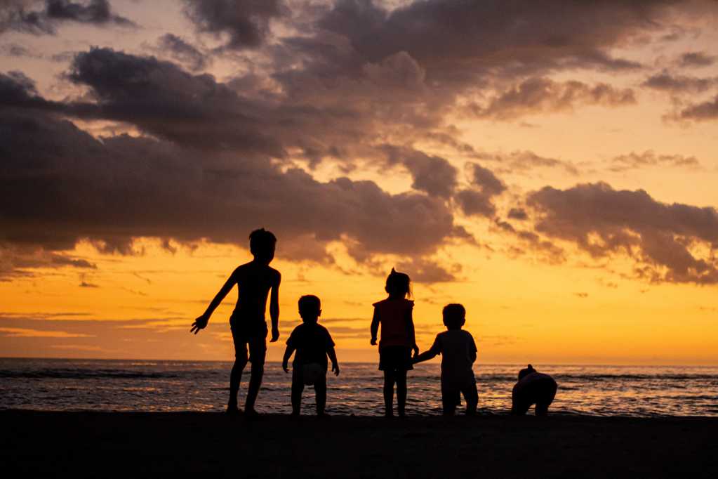 黄昏时沙滩上儿童们剪影图片