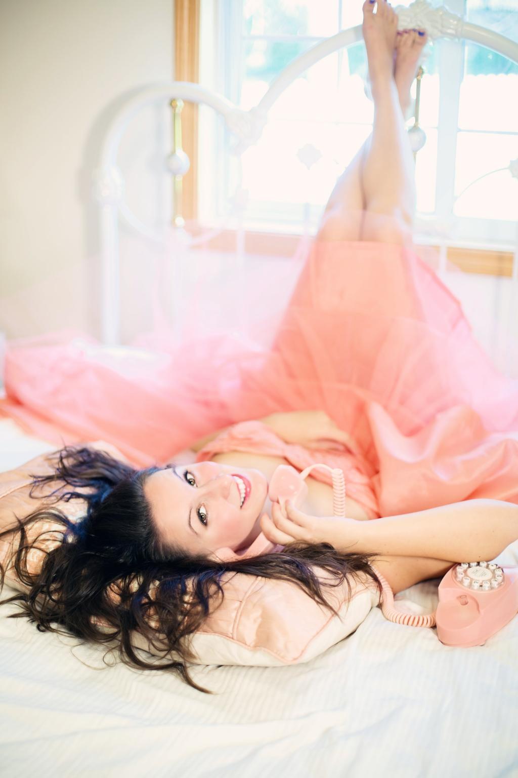 女人穿着粉红色的衣服,躺在白色的床垫高清壁纸