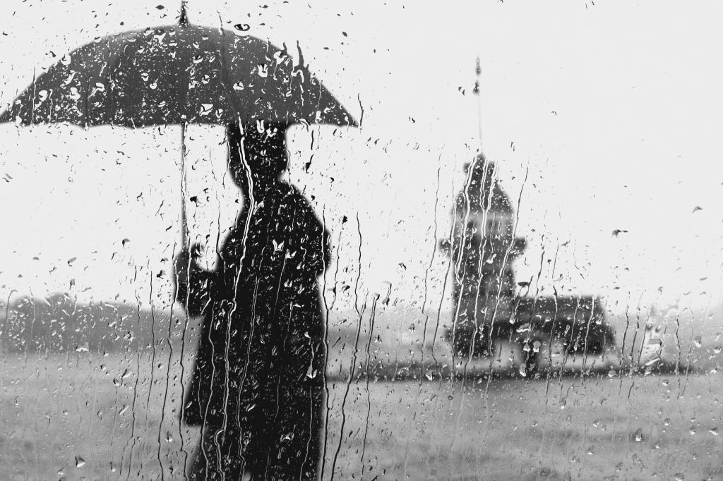 在大雨期间持有雨伞附近的人的灰色照片高清壁纸