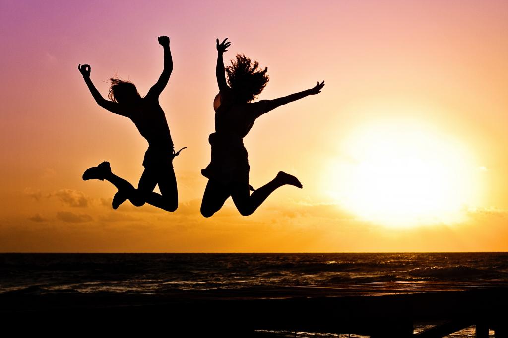 两个女人在海边反对日落高清壁纸跳跃