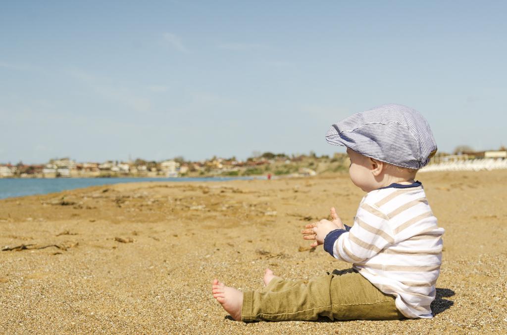 婴儿在白色长袖坐在海滩旁边的沙滩上白天高清壁纸