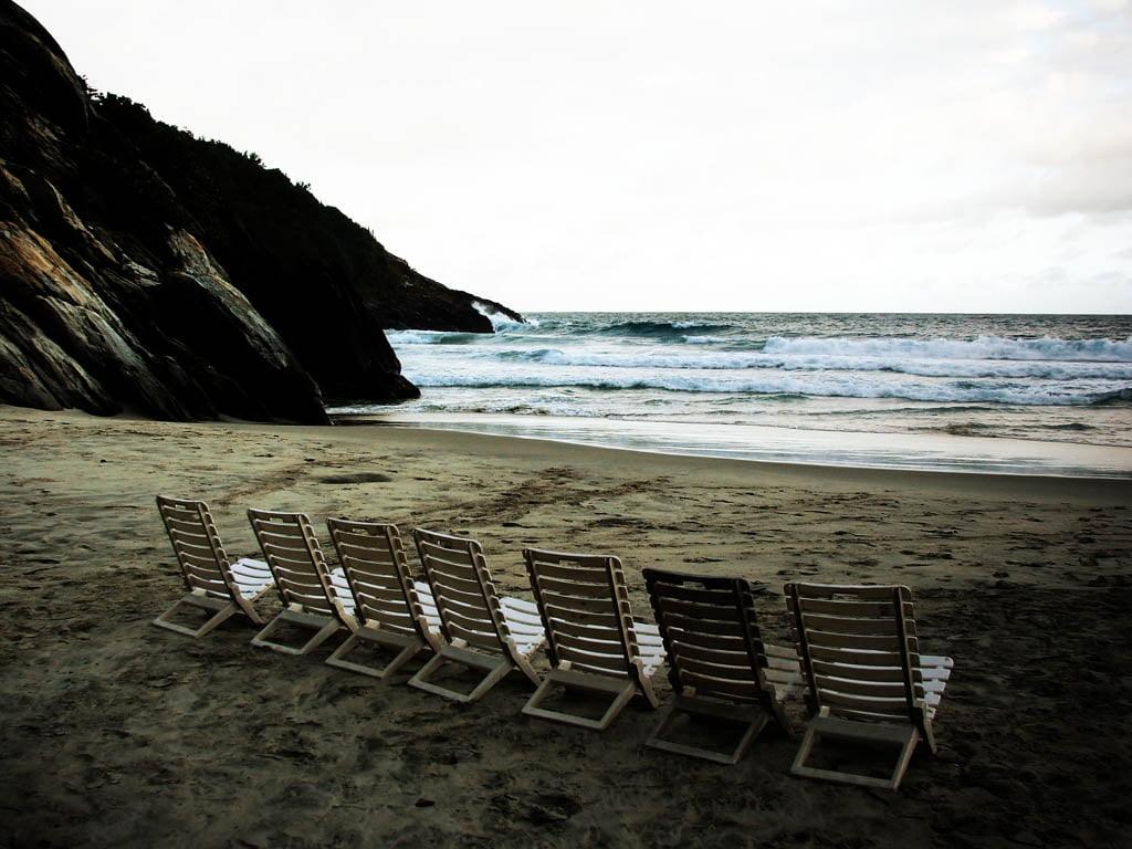 白色的天空下的海洋附近的白色沙滩躺椅高清壁纸