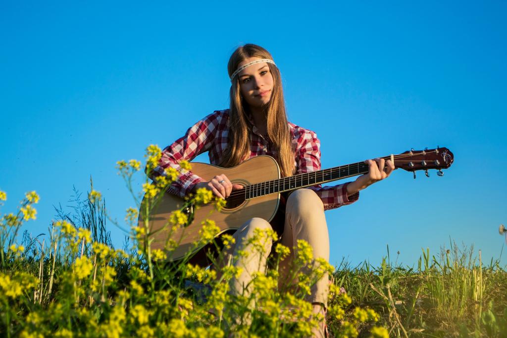 女人在白色和红色方格按钮了衬衫弹吉他附近黄色的花在白天下蓝色的天空高清壁纸