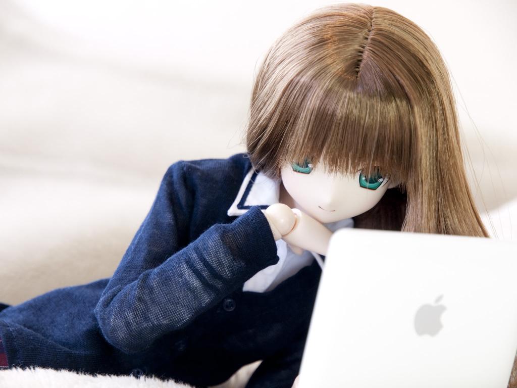 女人机器人穿着金色的头发和蓝色和白色的西装外套,看着MacBook白色,同时躺在床上高清壁纸