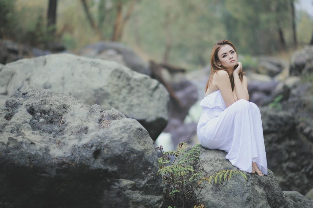 女人穿着白色的礼服,坐在岩层上高清壁纸