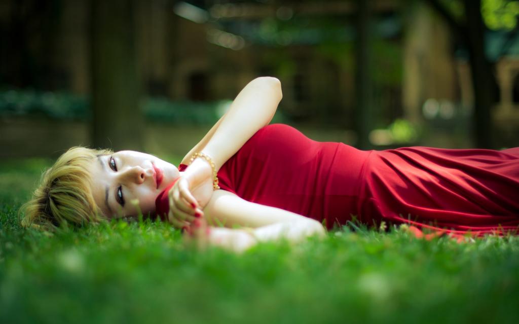 女人穿着红色躺在绿草高清壁纸的景深