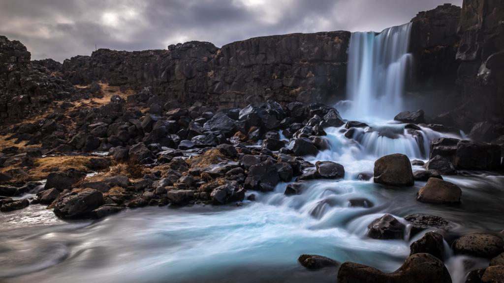 时间推移摄影的水落在厚厚的云层,冰岛高清壁纸下的石头包围