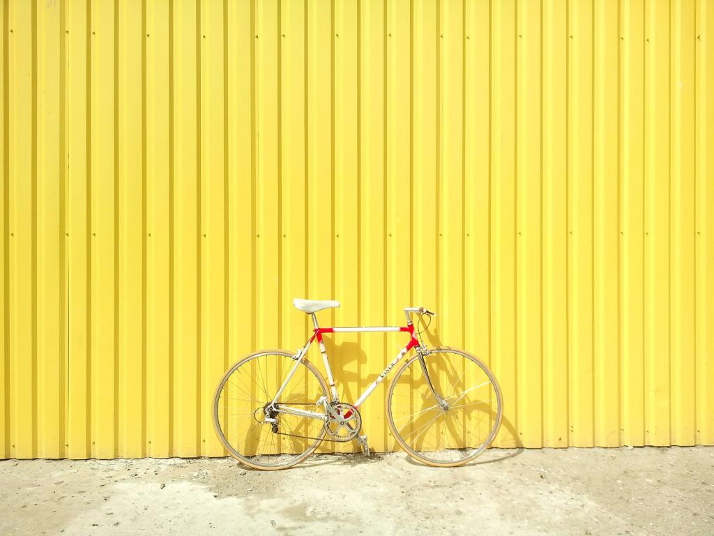 白色和红色的刚性自行车停在黄色漆墙高清壁纸旁边