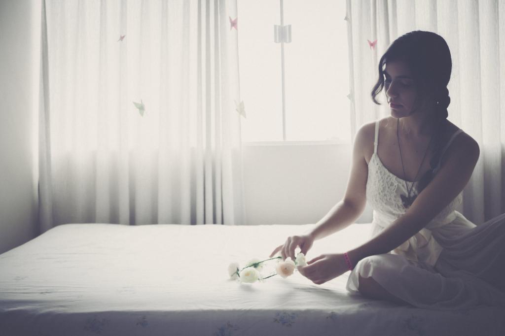 女人抱着白色的花重音头饰坐在床上高清壁纸