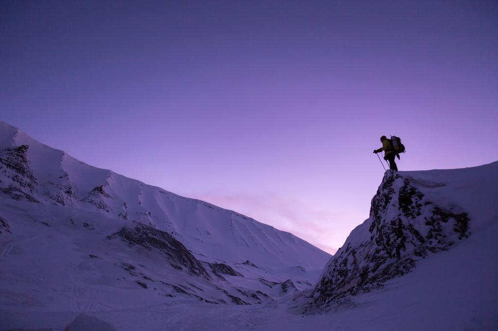 男子穿着背包拿着滑雪杆低角度照片附近的雪加盖的悬崖高清壁纸