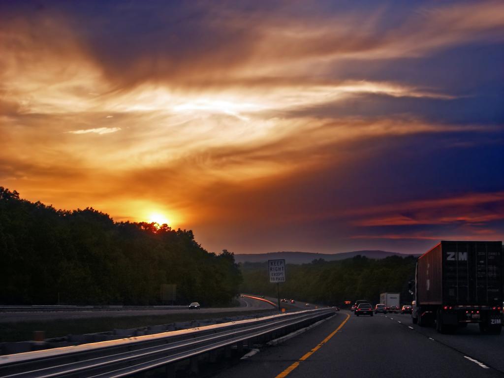 在日落时分的高速公路上的红色容器货车高清壁纸