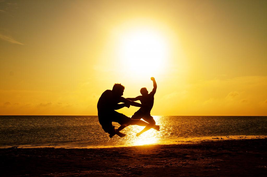 两名男子在金色的小时高清壁纸在海边跳跃的剪影照片