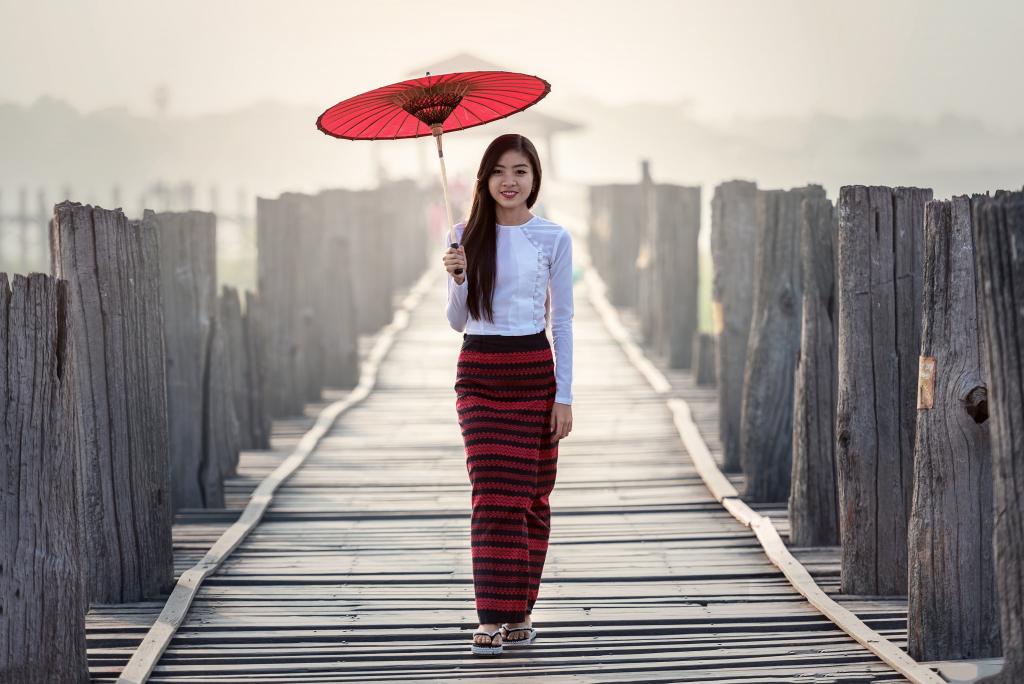 白色长袖衬衫和红色条纹裙子拿着伞走在灰色的木头路径高清壁纸的女人