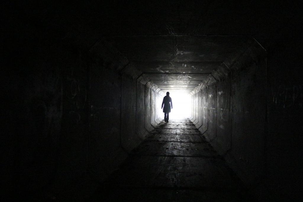 走在黑暗的隧道里的人与远距离高清壁纸上的白光