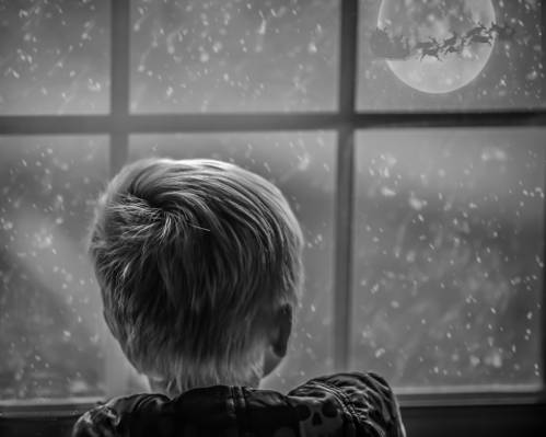 在雪和圣诞老人​​骑雪橇高清壁纸期间看窗外的男孩