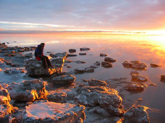 在金色的小时,锚地,阿拉斯加高清壁纸期间坐在海岸线附近的岩石上的人