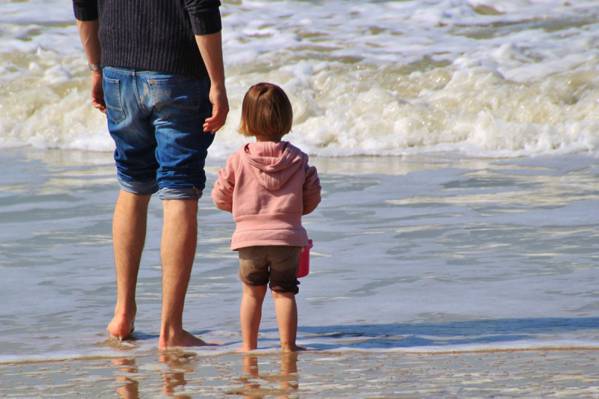 男子在蓝色牛仔短裤旁边的女孩在粉红色连帽衫在海滩期间白天高清壁纸