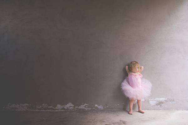 女孩穿着粉红色的连衣裙,在白天高清壁纸倾斜在墙上
