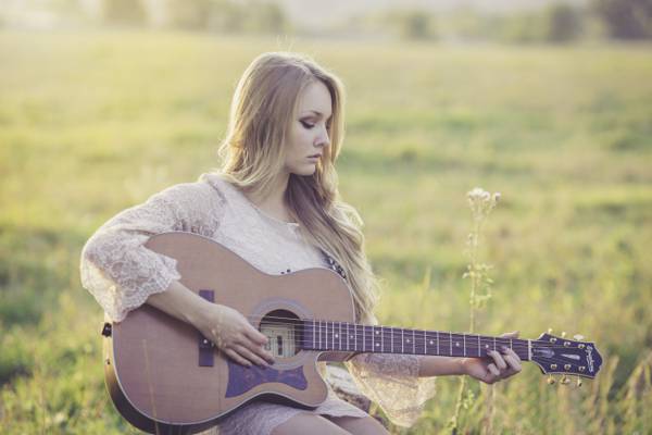 女人在日光下高清壁纸草地上玩吉他
