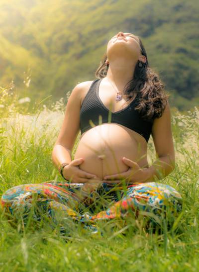 怀孕的女人穿着黑色胸罩和蓝绿色的裤子坐在白色的高清壁纸绿草场