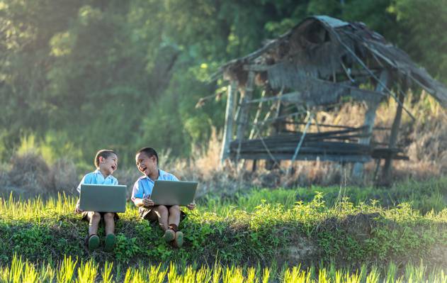 两个男孩在棕色尼帕小屋前使用笔记本电脑高清壁纸