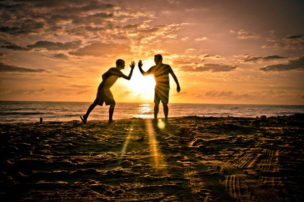 日落时高清壁纸上的两个男人在海滩上的剪影
