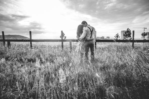 夫妇在木篱笆旁边的草地上拥抱高清壁纸