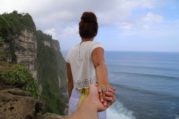 女人穿着白衬衫和紫色底部举行人的手站附近水体HD壁纸的悬崖上
