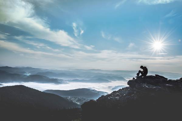 人坐在积云下的积云峰前的山顶上的剪影照片和清晰的蓝色冷静的天空高清壁纸