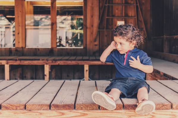 男孩坐在棕色的木地板,而按住右耳高清壁纸