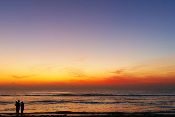 日落时高清壁纸的两个人在海滩上的剪影