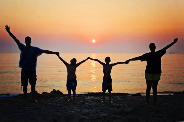 男人的剪影,与他们的两个男孩举行的同时在日落期间举起双手在海滩的女人高清壁纸