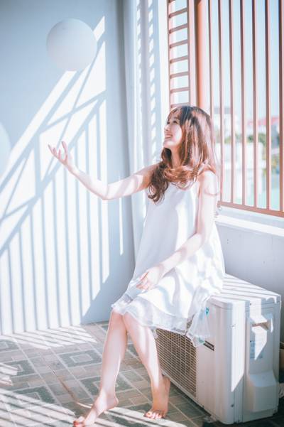 女人穿着白色的意大利面条带裙子坐在白色的空气逆变器白天高清壁纸