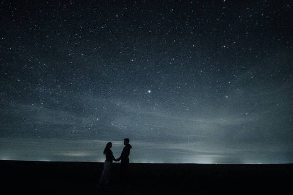 一个男人和女人的剪影照片抱着彼此的手与充满恒星的高清壁纸的天空