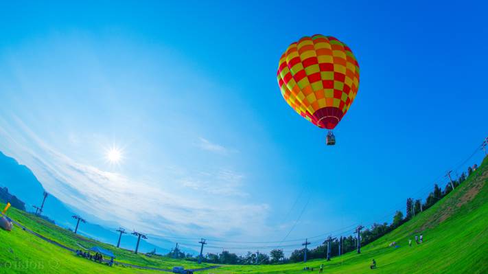 蠕虫的眼睛视图的热气球飞行在绿草领域在晴天和晴朗的天空高清壁纸