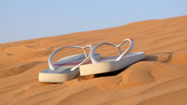 在白天高清壁纸沙漠上的两个白色人字拖鞋