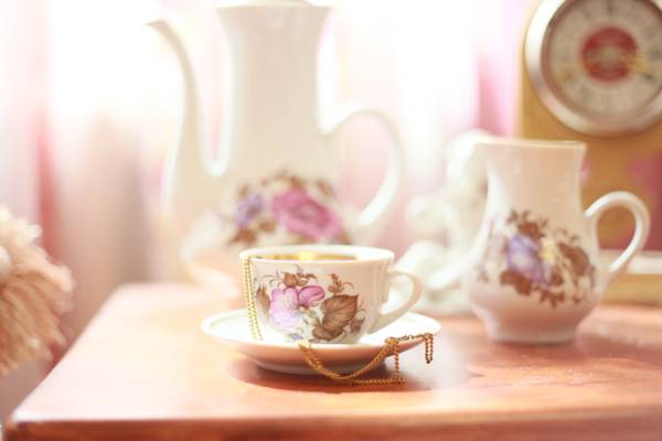 自动对焦摄影的白色花卉茶杯上的白色陶瓷碟与金项链放在它高清壁纸