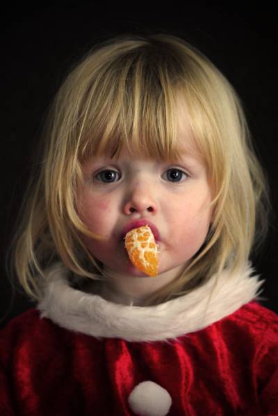 女孩吃切片的橙色水果穿着红色圣诞老人的衣服高清壁纸