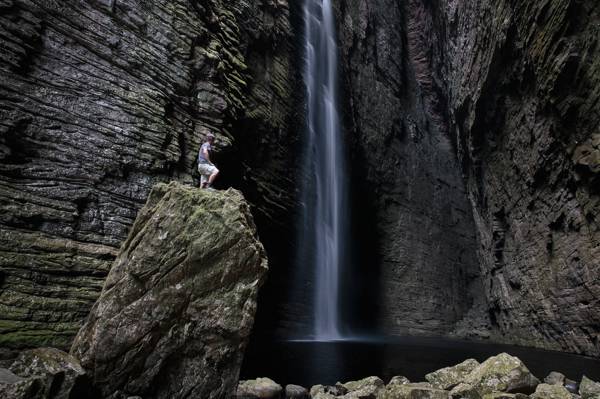 男子站在瀑布高清壁纸附近的岩石悬崖上
