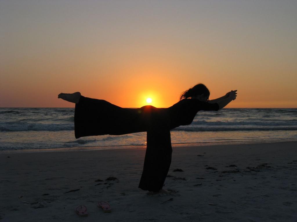 在日落期间做瑜伽在海滩高清壁纸的女人的剪影