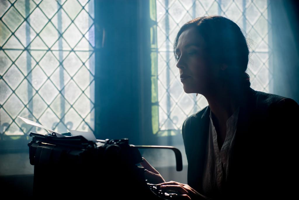 女子坐在黑暗的房间内的打字机附近高清壁纸