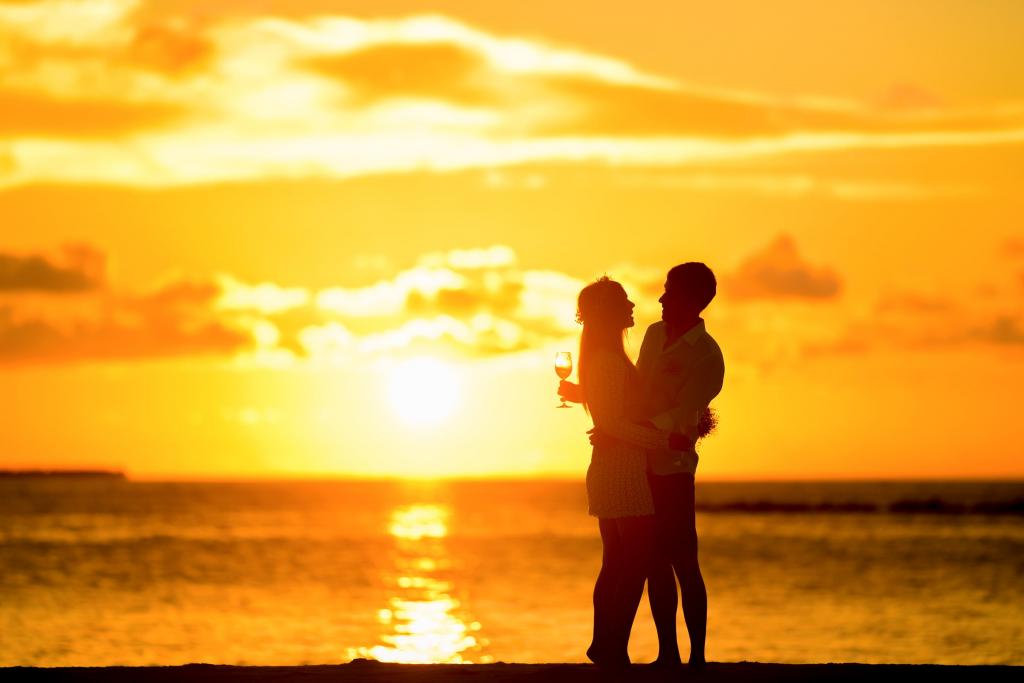 夫妇站在海边在日落期间拥抱对方高清壁纸