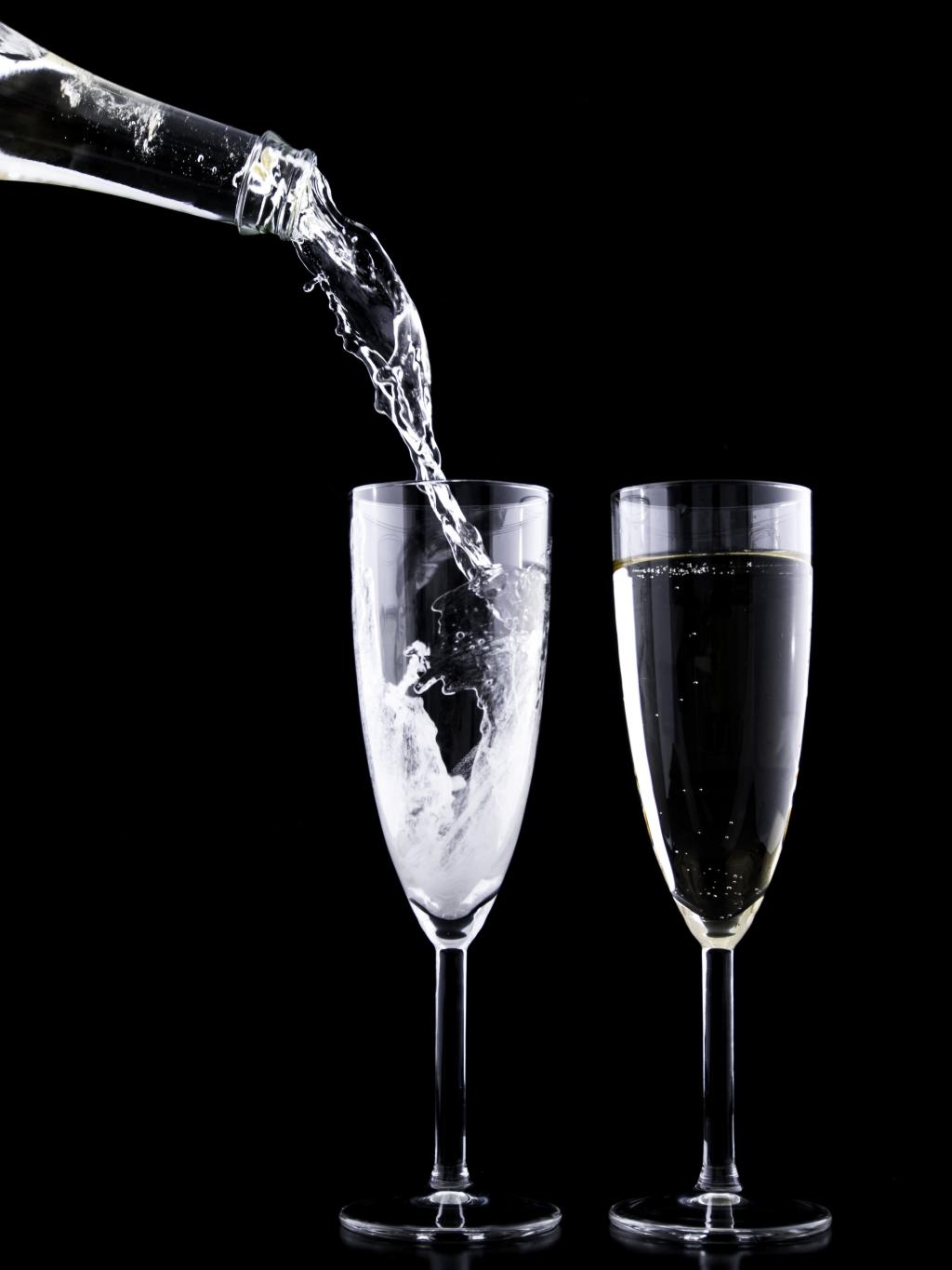 玻璃瓶倒在两个清澈的玻璃香槟笛子液体高清壁纸