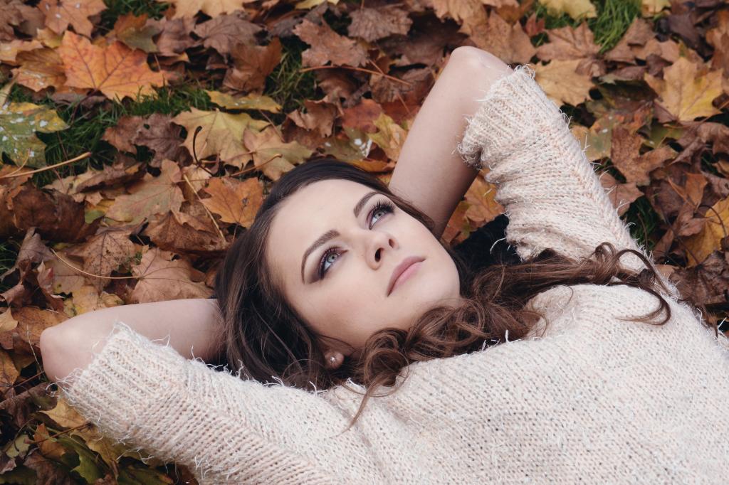 女人在米色针织衬衫躺在地上,棕色的叶子高清壁纸