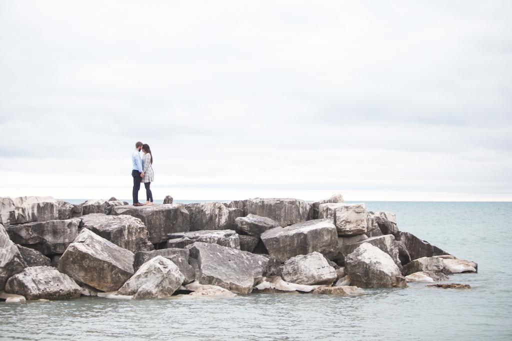 夫妇站在白色的天空高清壁纸下的海水灰色岩层上
