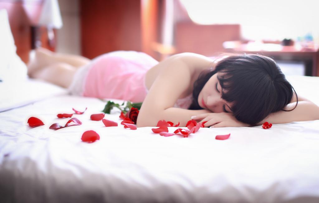 女人躺在床上用红色的花瓣高清壁纸