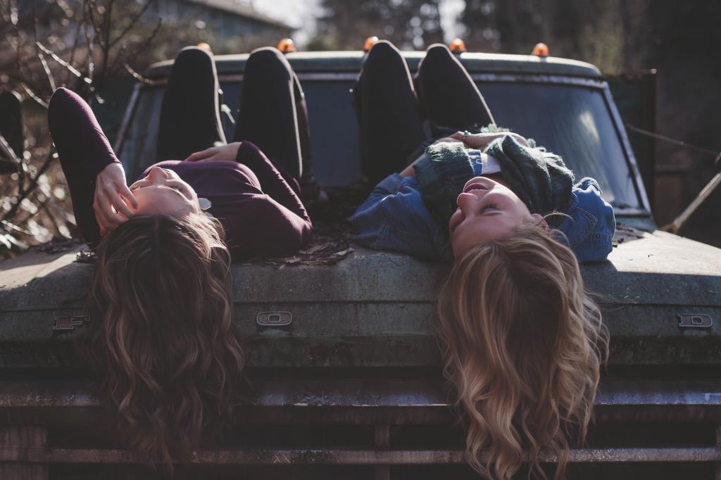 两个女孩躺在汽车引擎盖白天高清壁纸
